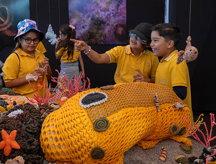 Niños observan distintas figuras tejidas a crochet y que forman parte de ma muestra Tramares.