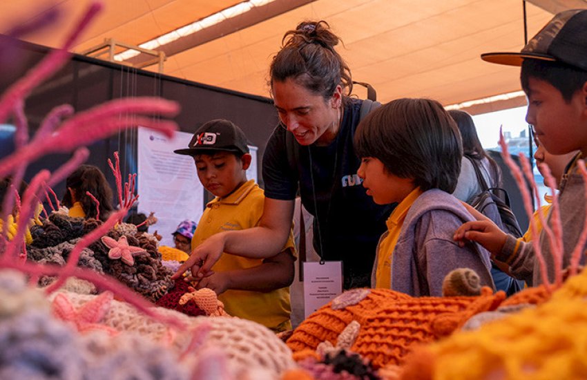 La investigadora de Núcleo NUTME, Celeste Kroeger, le muestra a unos niños la exposición