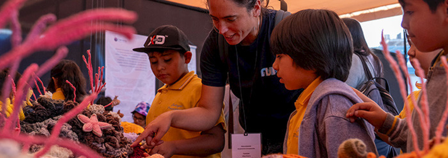 La investigadora de Núcleo NUTME, Celeste Kroeger, le muestra a unos niños la exposición